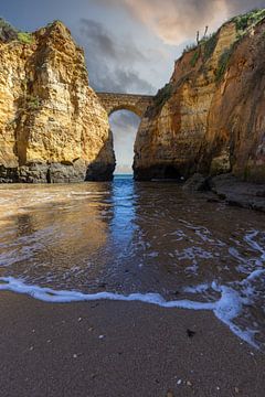 Zonsondergang bij Praia da Caldeira. Kliffen een brug over de zee van een baai bij Lagos, Portugal van Fotos by Jan Wehnert