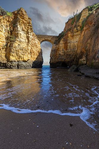 Zonsondergang bij Praia da Caldeira. Kliffen een brug over de zee van een baai bij Lagos, Portugal