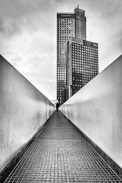 Schwarz-Weiß-Fotografie eines Hochhauses in Rotterdam Holland mit einer Fußgängerbrücke im Vordergru