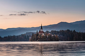 Bled, Silhouette vor glühendem Morgenhimmel von Daan Duvillier | Stimmungsvolle Stadt- und Landschaftsfotos
