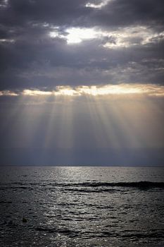 Beach with sea and threatening sky with sunbeams from sunset on Crete, Greece