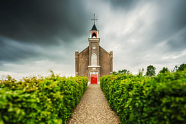 A historic little brick church with a symmetrical garden path by Fotografiecor .nl