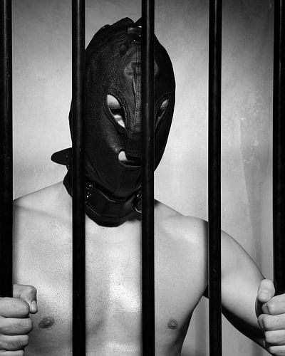 Man achter gevangenis tralies in onderdanige fetisj stijl