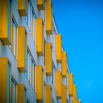 Flat met gele ramen voor een baluwe lucht.