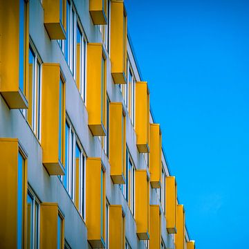 Wohnung mit gelben Fenstern vor einem blauen Himmel. von Jeroen