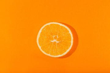 Schijfje sinaasappel tegen een oranje achtergond van Ans van Heck