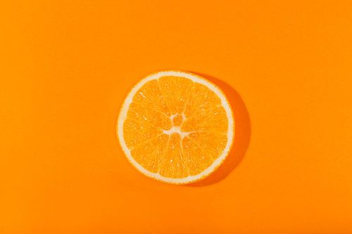 Schijfje sinaasappel tegen een oranje achtergond