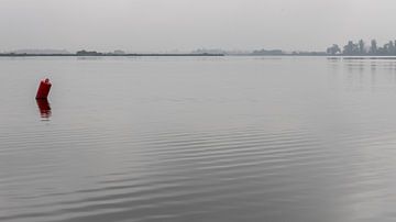 The red barrel in the middle of the windless water by Hans de Waay