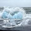 Blauwe ijsschots op vulkaan strand Jokulsarlon met een golf die net op de schots breekt sur Jutta Klassen