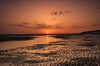 Ondergaande zon kleurt alles rood op het strand