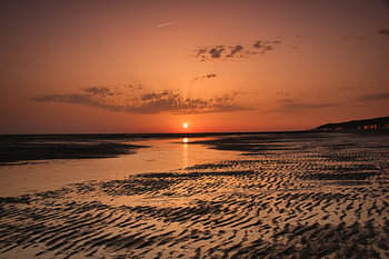 Die untergehende Sonne färbt alles am Strand rot