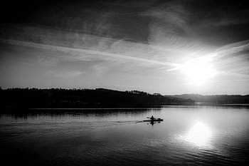 lonely man paddling on Baldeneysee at sunset in black and white
