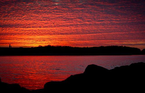 Zonsondergang in Zeeland, de wolkenlucht weerspiegeld in het water
