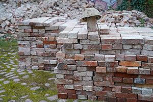 gestapelte Ziegel und alter Bauhelm auf einer Baustelle