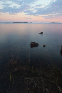rosa Wasser und Gletscherstreifen auf Felsen und rosa Sonnenuntergang Skandinavien, Karelien von Michael Semenov