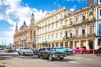 Oldtimer cars drive through the bustling streets of Havana in Cuba