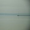 A long lonely footbridge reaches into the foggy Ammersee in Bavaria. Mountain ranges on the horizon von LuCreator
