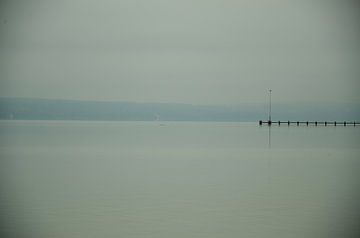 A long lonely footbridge reaches into the foggy Ammersee in Bavaria. Mountain ranges on the horizon von LuCreator