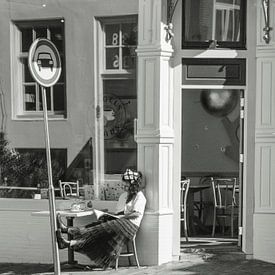 Junge Frau liest draußen in der Sonne ein Buch von Bart van Lier
