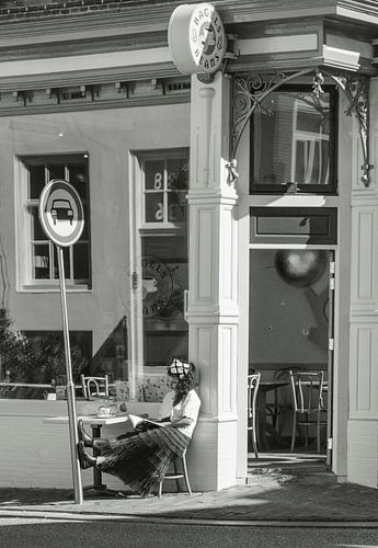 Junge Frau liest draußen in der Sonne ein Buch von Bart van Lier