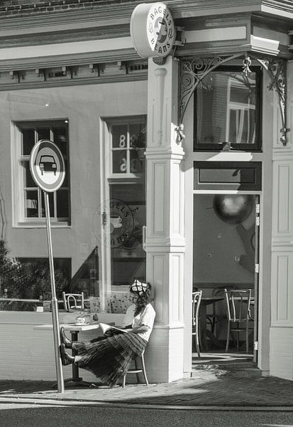 Junge Frau liest draußen in der Sonne ein Buch von Bart van Lier