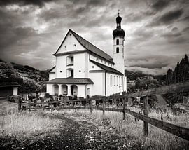 A white church on a dramatic, cloudy day in Austria by Riekus Reinders