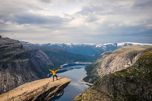 Trolltunga: Der gelbe Mann mit Blick auf den Ringedalsvannet und schneebedeckte Berge