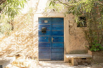 Blue wooden door in sunny street, Mediterranean ambience