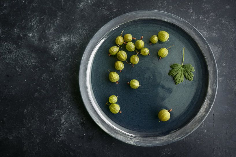 Quelques groseilles à maquereau biologiques fraîchement récoltées sur une plaque bleu foncé et un fo par Maren Winter