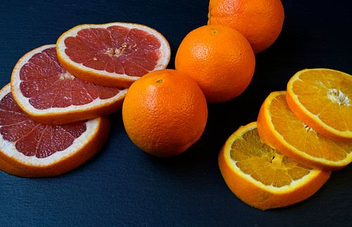 Grapefruit en sinaasappel in plakjes gesneden en gerangschikt op een zwarte serveerschaal