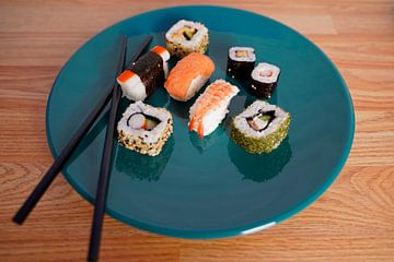 Sushi op een groen bord met eetstokjes