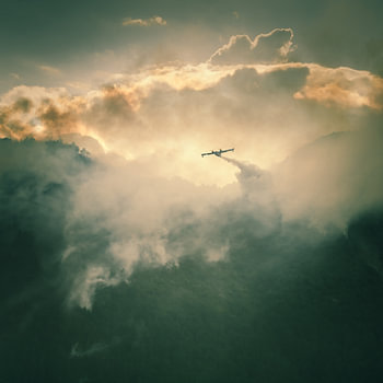 Ein Löschflugzeug entlädt seine Wasserladung in den Bergen