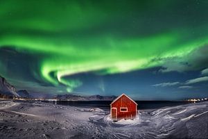 Rotes Holzhaus mit Polarlicht auf den Lofoten in Norwegen.