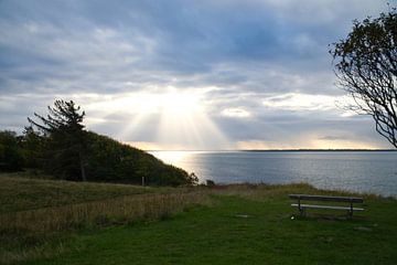 Zonnestralen breken de wolken in de zee in Denemarken van Martin Köbsch
