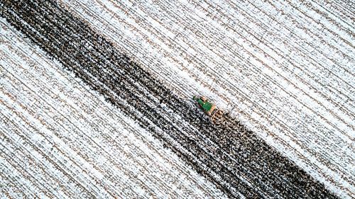 Tractor ploegt door besneeuwd akkerland