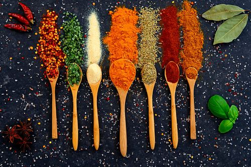 Fleurige specerijen en kruiden op houten lepels