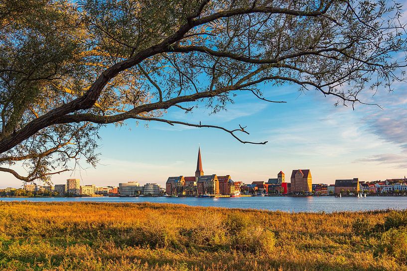 Uitzicht over de Warnow naar de Hanzestad Rostock bij avond van Rico Ködder