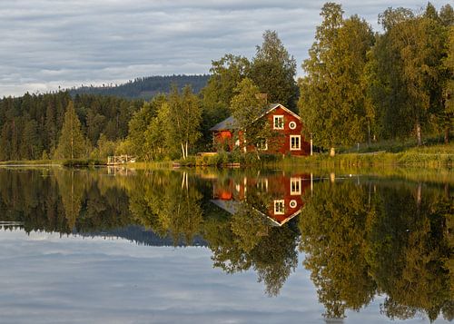 Zweedse stuga aan een kalm meer op een bewolkte zomerdag