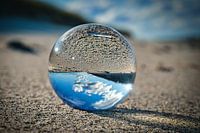 Glass ball on the beach of the Baltic Sea. Detailed close-up of the sphere with reflection of the la