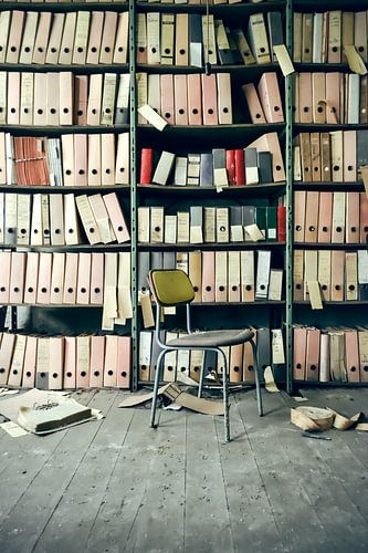 A shelf with folders and files in front of which stands a chair