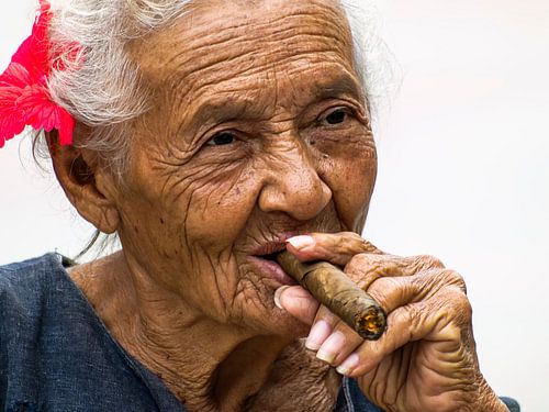 Elderly woman smokes cigar in Cuba