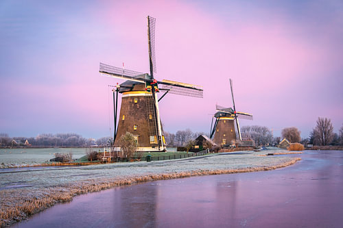 Zwei Windmühlen im Winter bei Sonnenaufgang in den Niederlanden