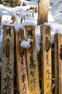 Houten paaltjes met tekst in de sneeuw van Mickéle Godderis