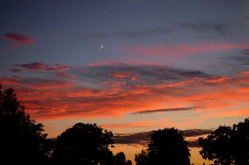 Sonnenuntergang mit Mond und orangefarbenen Wolken