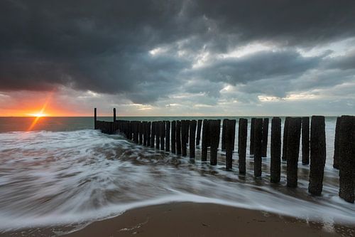 Hollandse wolkenlucht en typische golfbreker van houten palen langs de Zeeuwse kust