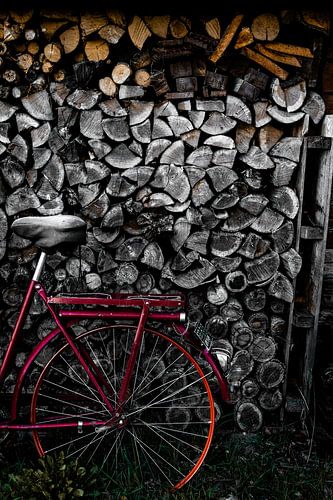 Un vélo rouge devant une grande pile de bûches. Prêt pour l'hiver à Zwolle, aux Pays-Bas