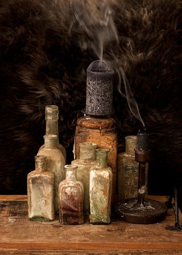 Still life with bottles and blown-out candles