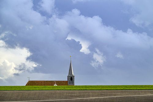 Kerk achter de Waddenzeedijk met wolken erboven