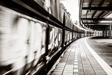 Lange trein suist langs het kromme perron en vervaagt door de beweging van Jan Willem de Groot Photography