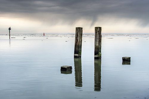 Het Wad bij Holwerd op een windstille dag en spiegelende palen.
